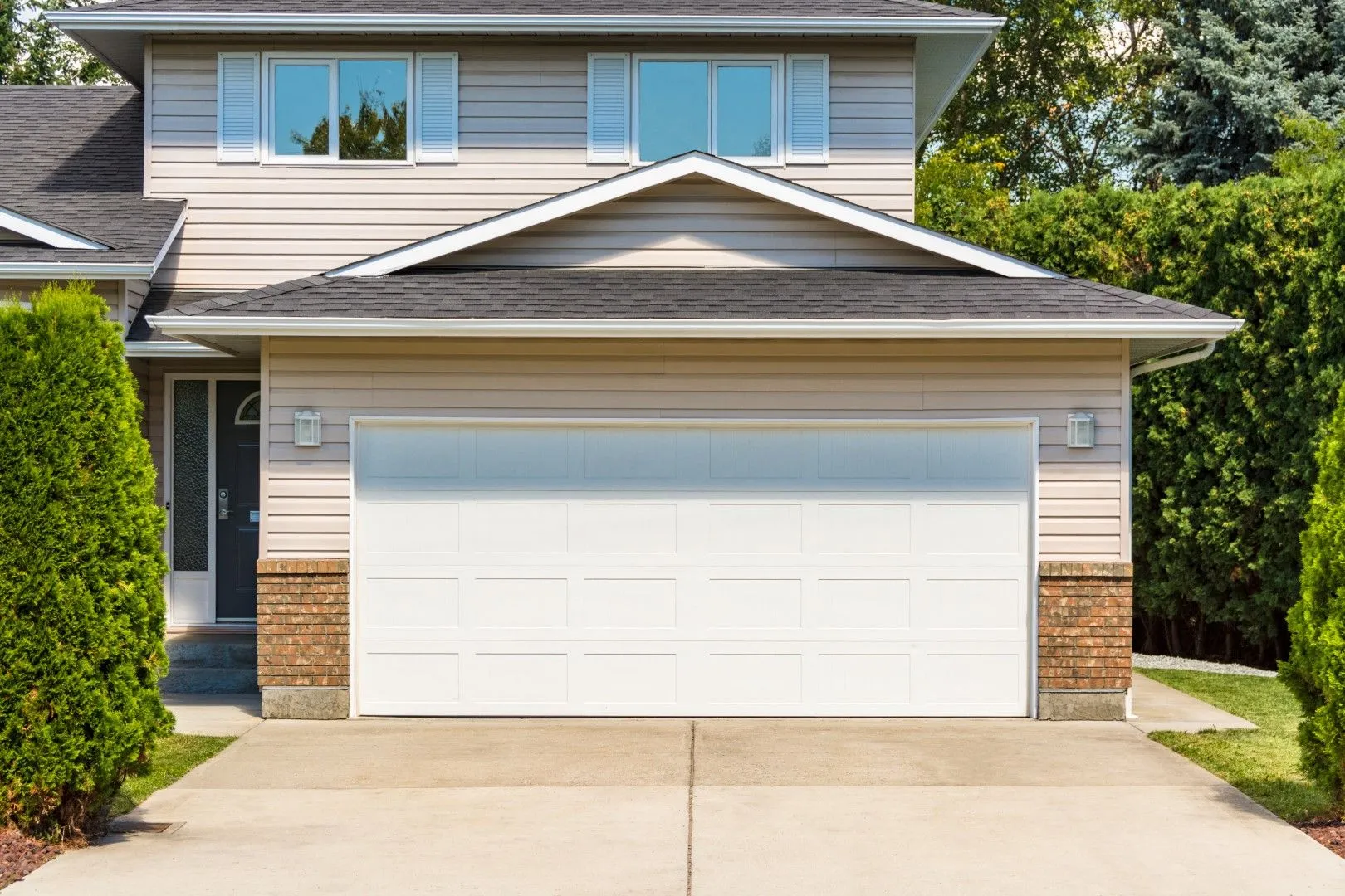 A large house with a white garage door and a driveway.